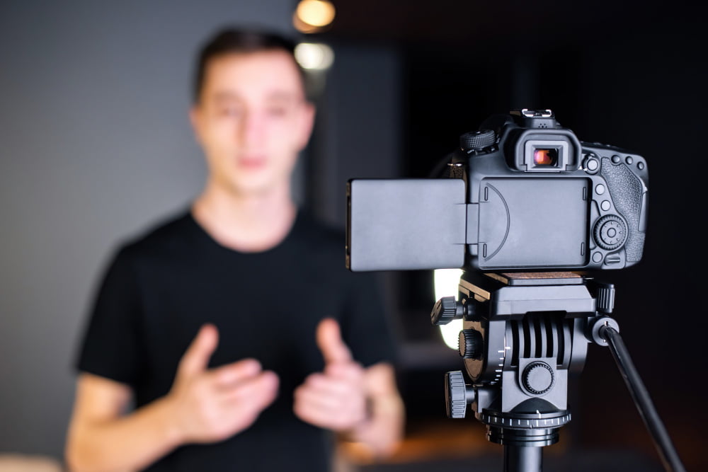 Como criar vídeos profissionais: Dicas para iniciantes 4 man talking camera recording himself vlog working from home young content creator