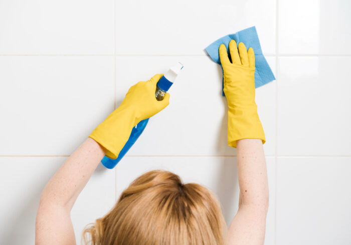 woman cleaning shower wall